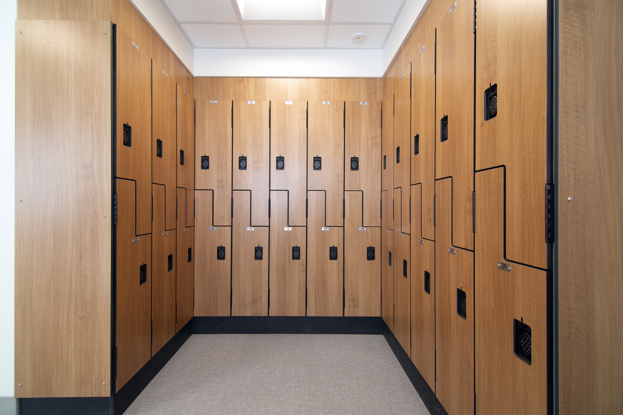 Wood locker room with numbered compartments and digital keypad locks lining both walls
