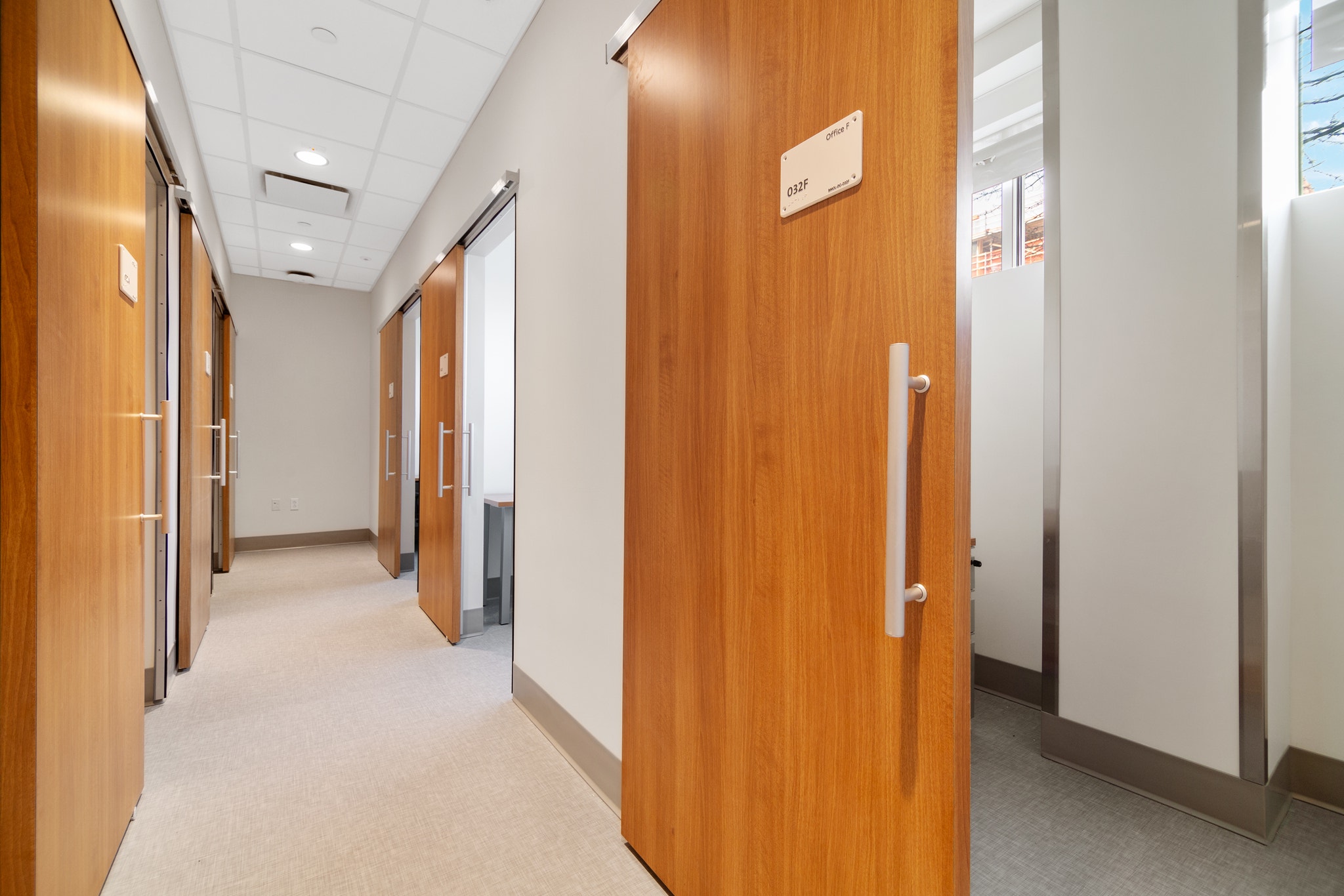 Hallway lined with wood sliding doors leading to private exam rooms and offices