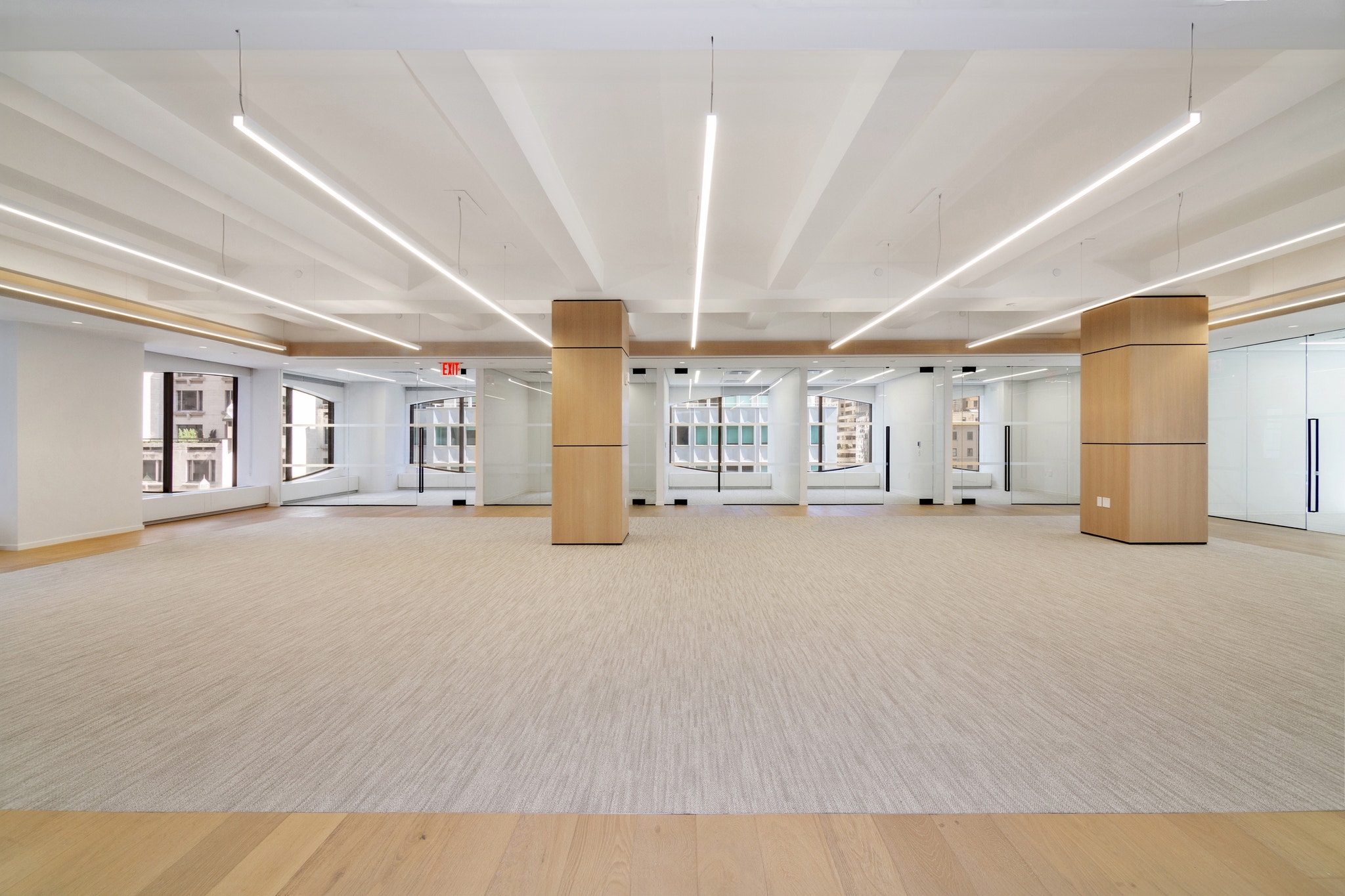 Open office floor with wood columns, glass conference rooms, and curved skyline window views
