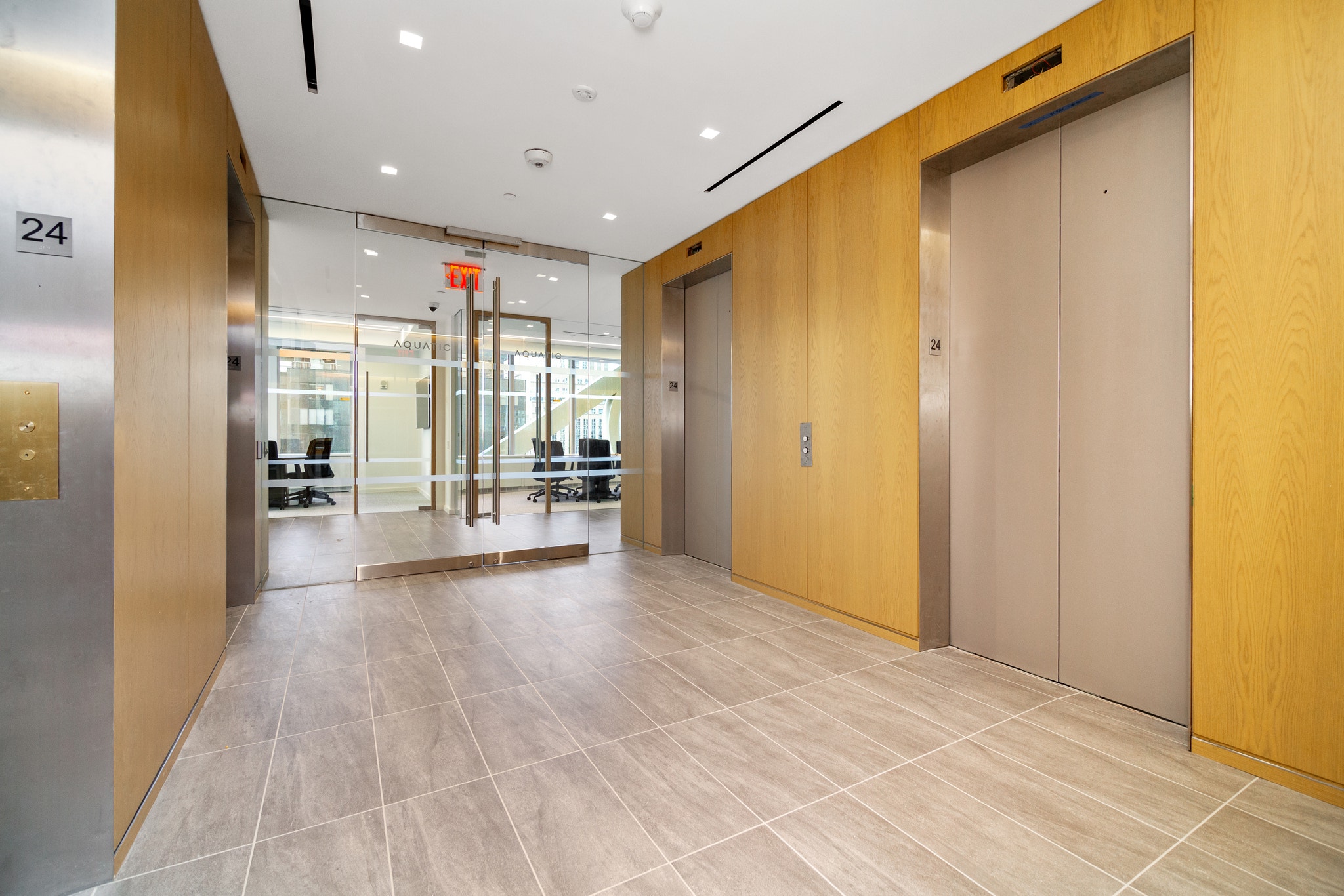 Elevator lobby on floor 24 with wood paneling and glass entrance to Aquatic office suite